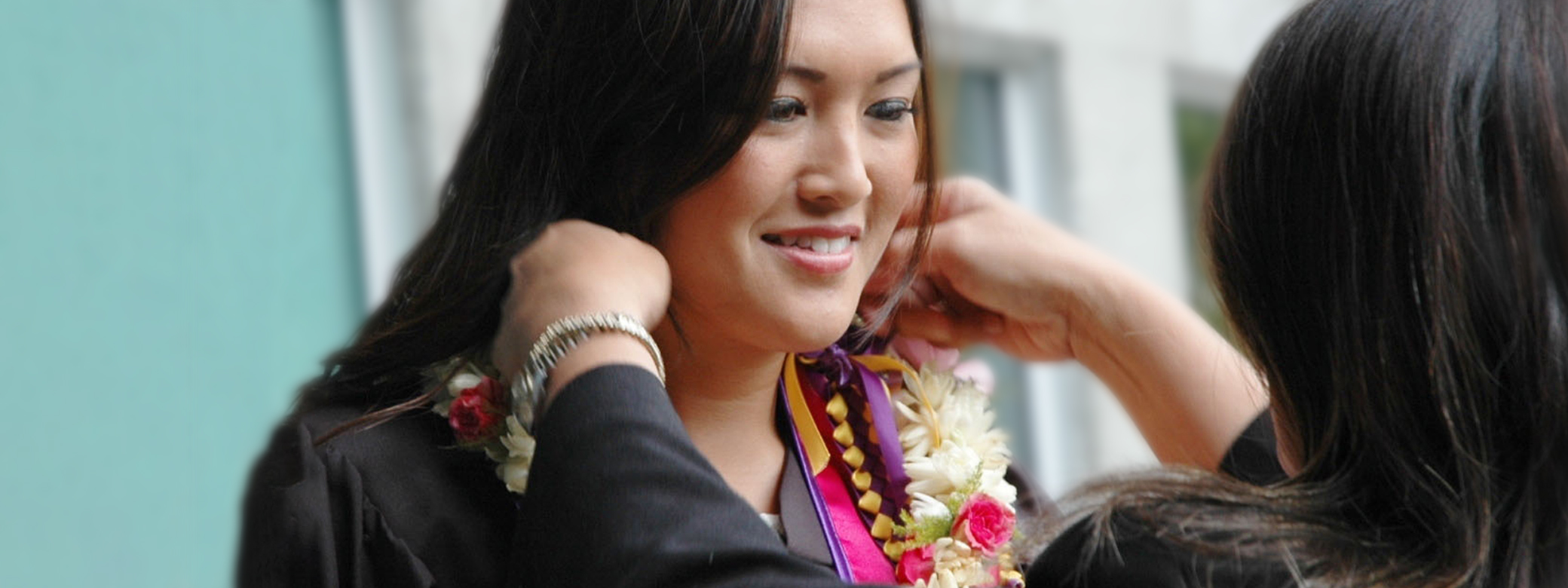 A graduation lei is being placed on a student.