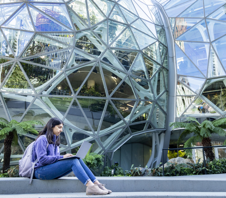 female student sitting with laptop in front of Amazon spheres