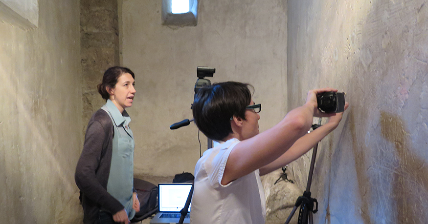 Sarah Levin-Richardson in a small space in Pompeii, using a handheld equipment to better view ancient graffiti on the walls. 